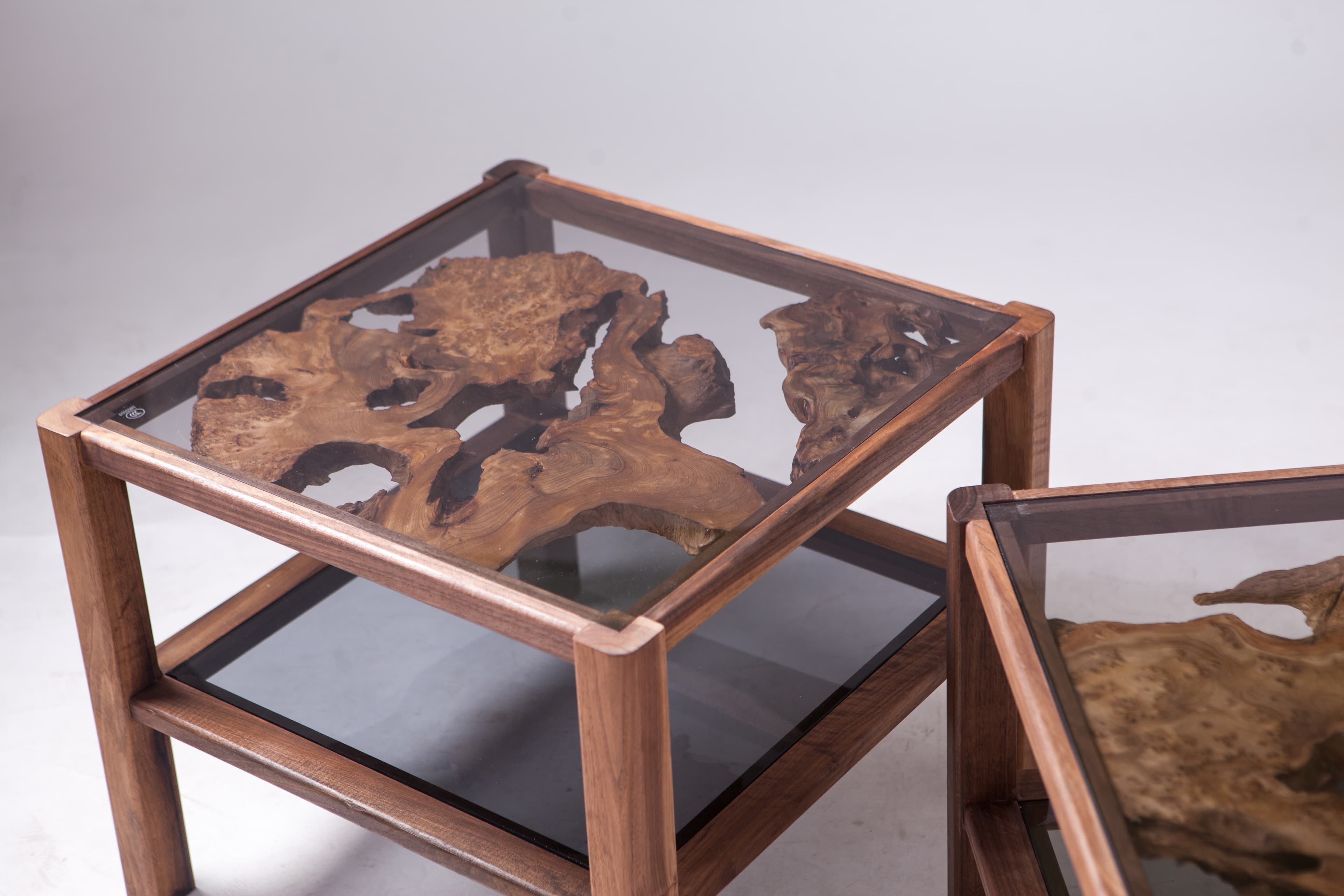Glass-topped wooden tables containing irregular natural wooden forms.