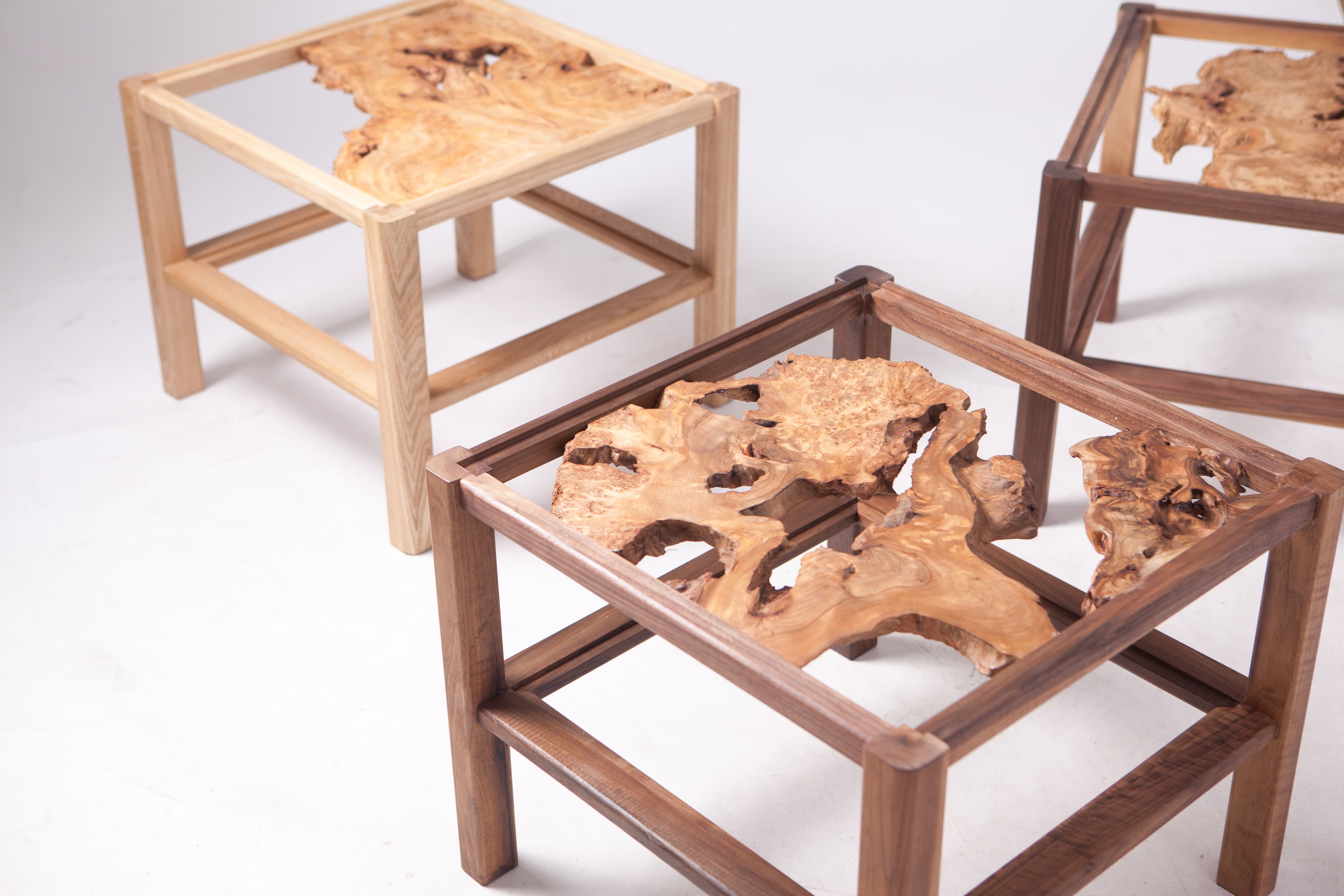 Group view of Product 03 tables with irregular natural wooden forms.