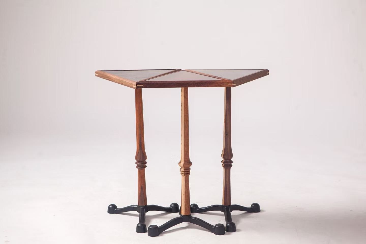 Three slender wooden tables arranged against a pale studio background.