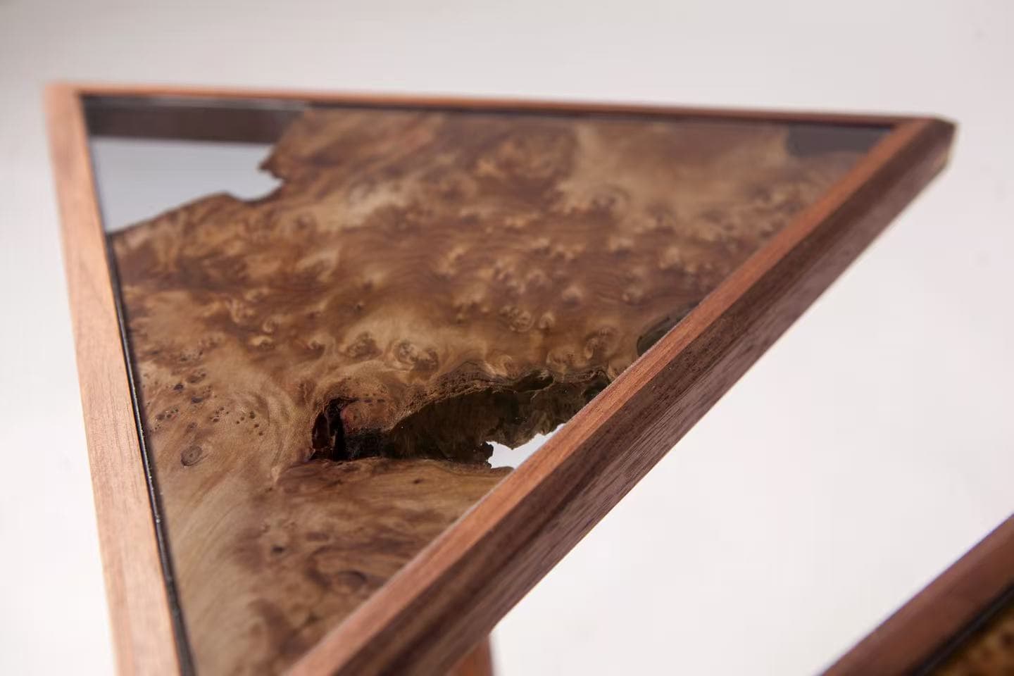 Close view of Product 04's triangular glass top and natural wood detail.